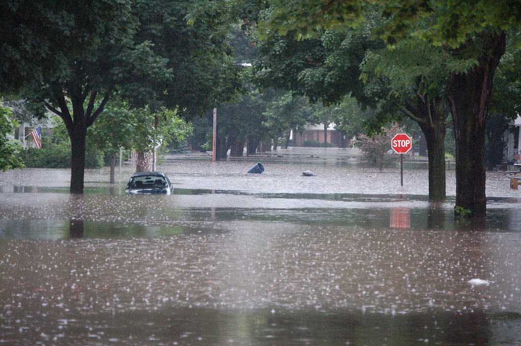 Flooded residential neighborhood with submerged cars and standing water covering streets during severe flooding emergency