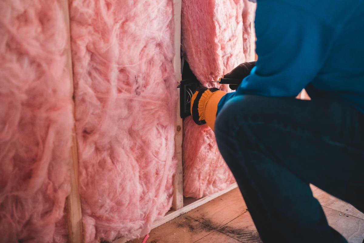 Technician installing wall insulation during reconstruction and rebuild work