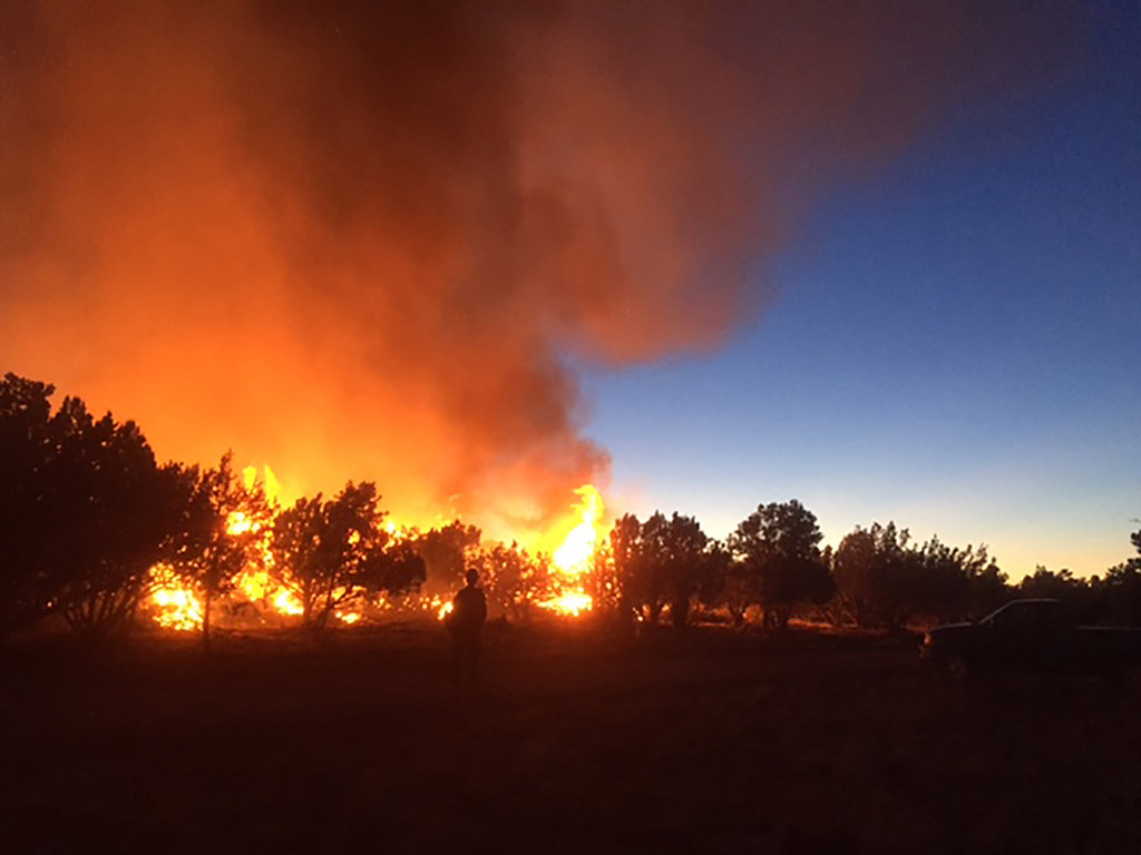 Active wildfire burning across a hillside with heavy smoke rising in Utah