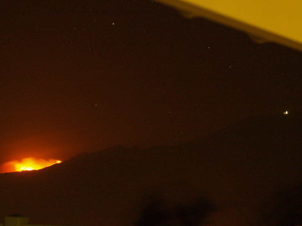 Wildfire glowing on a mountainside at night near residential areas in Utah